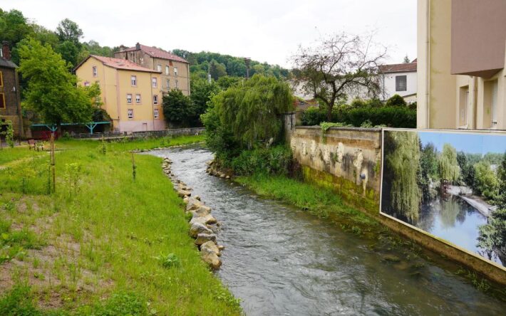 Pour habiller le mur du canal usinier, une fresque avec les photos anciennes du canal a été installée à côté d’un revêtement en planche - Crédits photo : Banque des Territoires